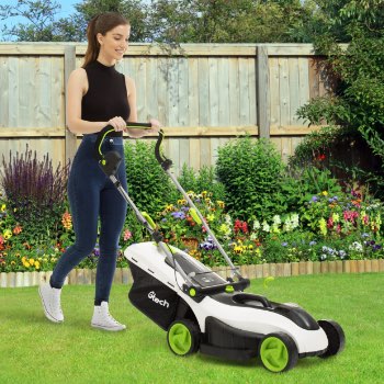 woman cutting grass next to flower bed with cordless mower