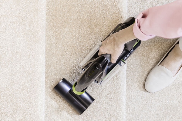 Woman cleaning kitchen surface with Gtech Multi vacuum cleaner