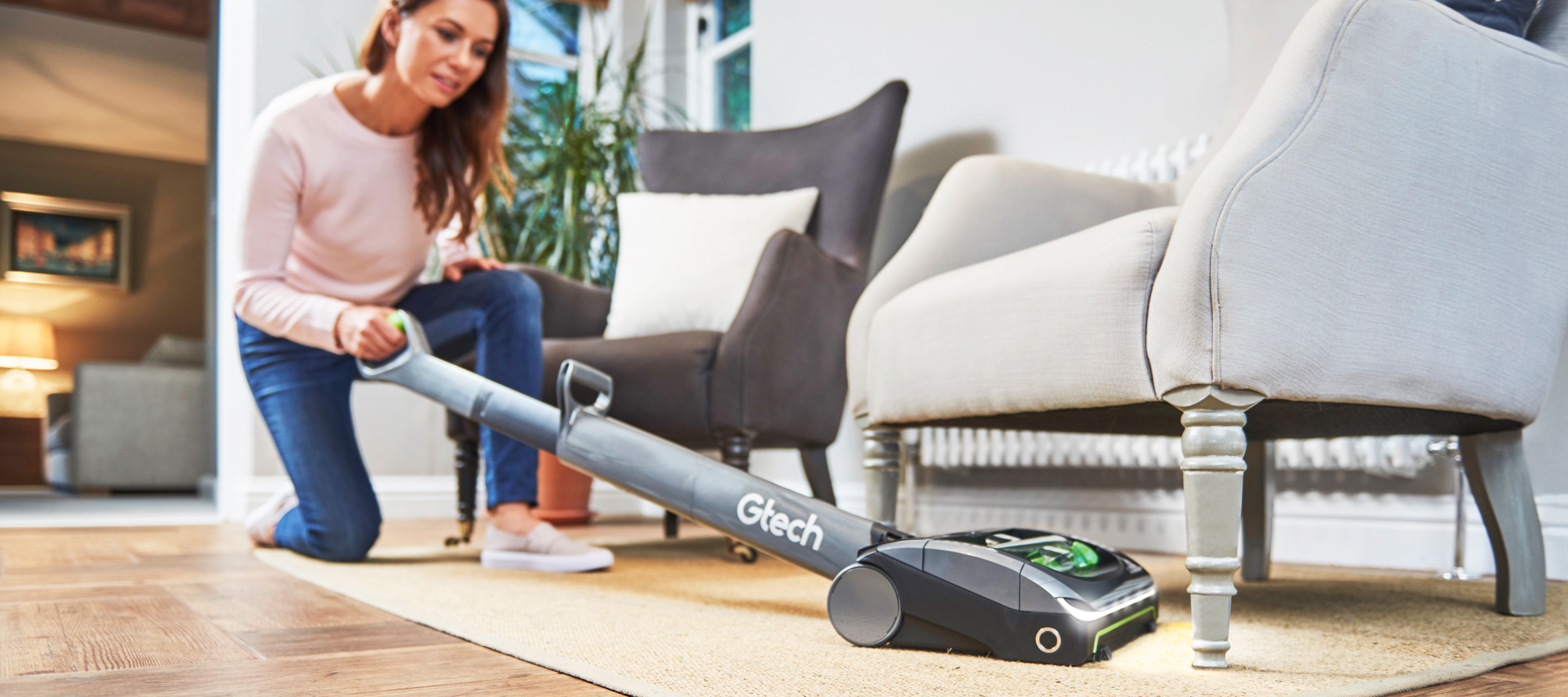 Women uses AirRam cordless vacuum cleaner to reach under sofa