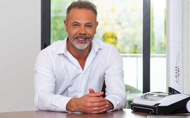 Gtech founder and inventor Nick Grey in his office with the AirRAM 3 cordless vacuum, demonstrating the brand's focus on real-life cleaning performance.